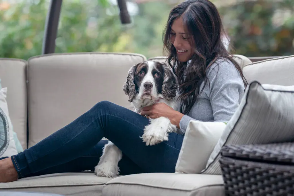 Woman and dog sitting on outdoor furniture